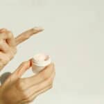 A close-up image showing hands applying facial cream, reflecting a minimalist skincare routine.