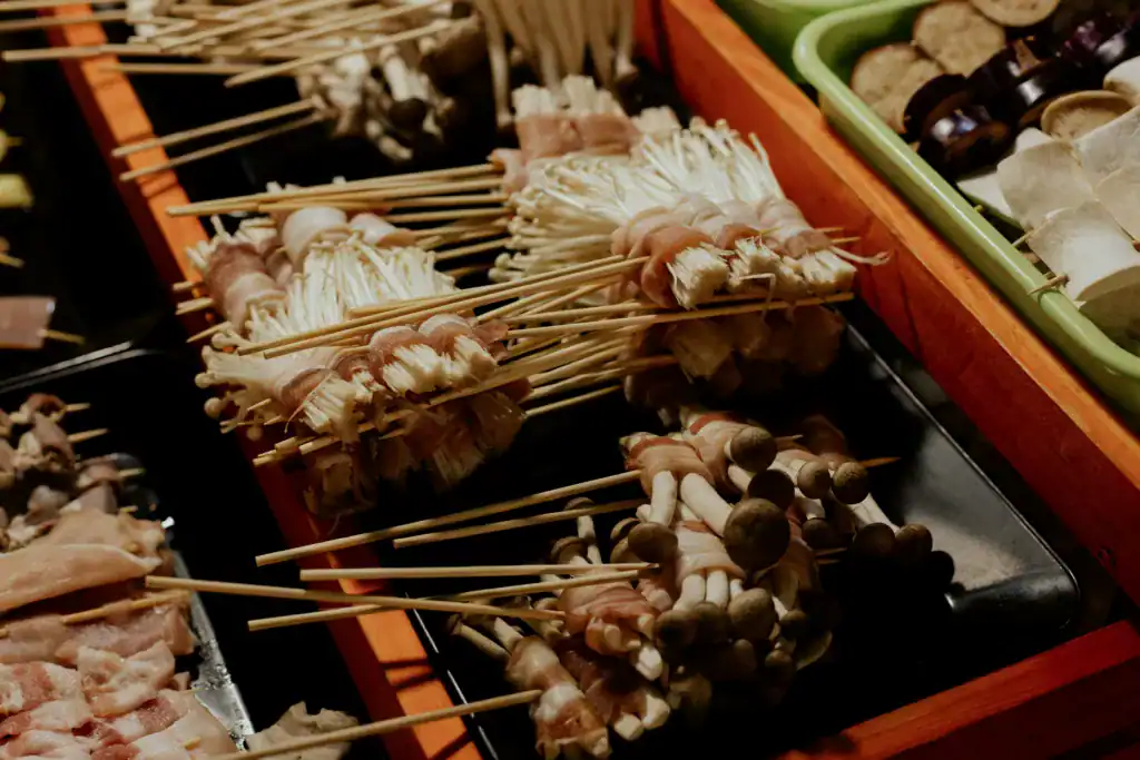 A vibrant display of skewered mushrooms wrapped in bacon at a street food stall, showcasing diverse Asian cuisine.