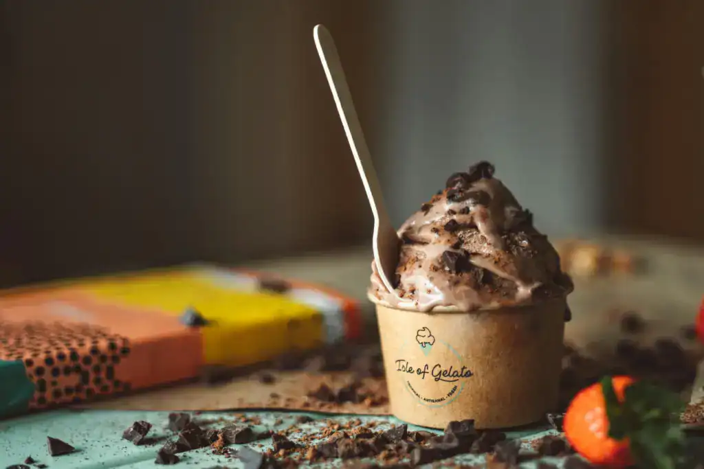 Indulge in creamy chocolate gelato with chocolate chunks, served in an eco-friendly paper cup for a delightful treat.