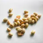 Close-up image of soybeans scattered on a white surface.